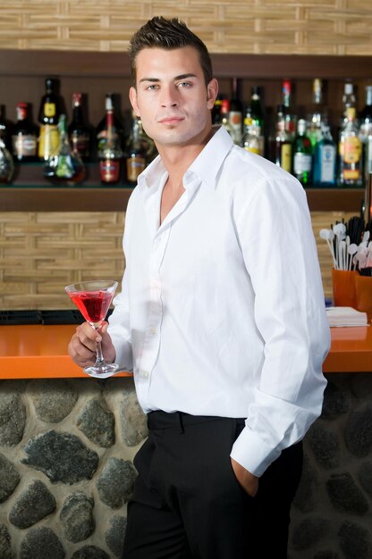 Homem em um bar com martini vermelho