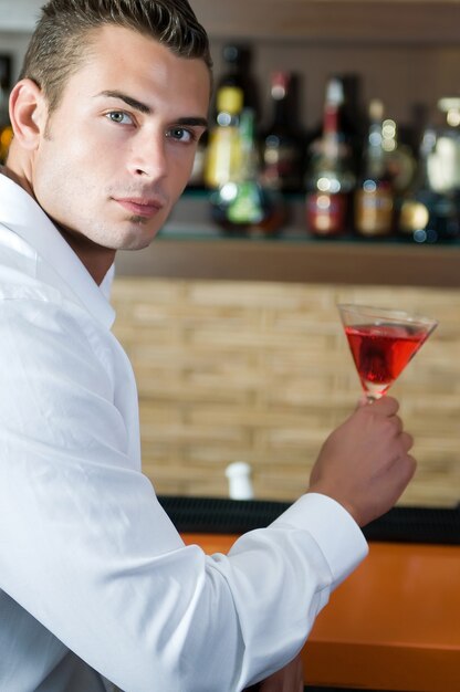 Homem em um bar com martini vermelho