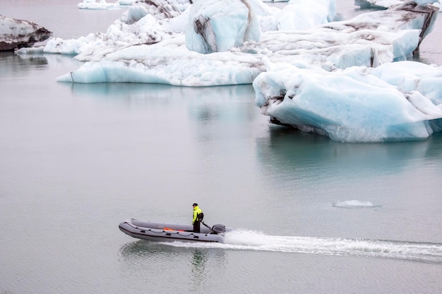 Homem em um barco a motor veloz navegando em uma lagoa glaciar na islândia