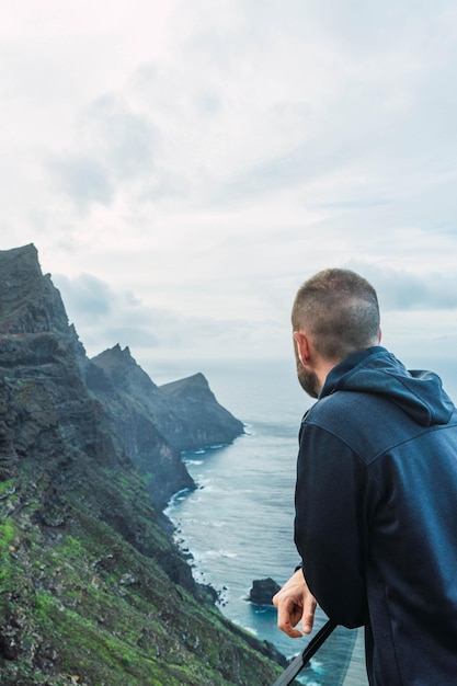 Homem em um mirante observando a paisagem marítima em um dia nublado