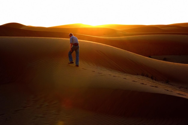Foto homem em uma duna de areia no deserto contra o céu