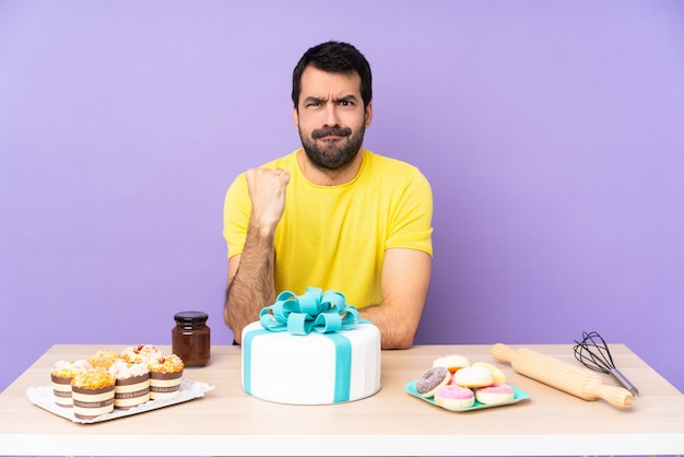 Homem em uma mesa com um bolo grande com gesto de raiva