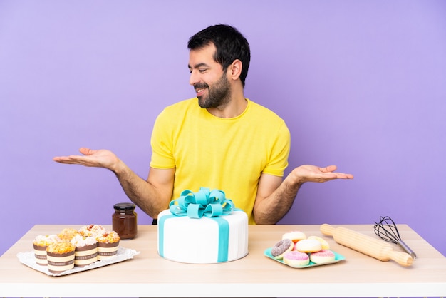 Homem em uma mesa com um grande bolo segurando copyspace com as duas mãos