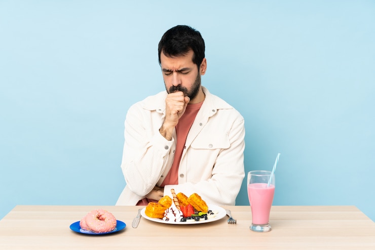 Foto homem em uma mesa tomando café da manhã waffles e um milk-shake está sofrendo de tosse e se sentindo mal