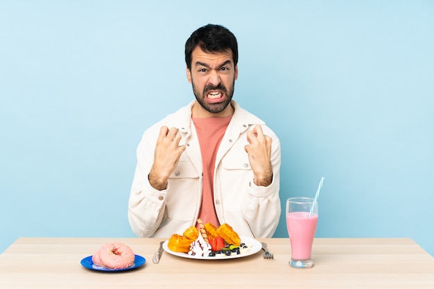 Homem em uma mesa tomando café da manhã waffles e um milk-shake frustrado por uma situação ruim
