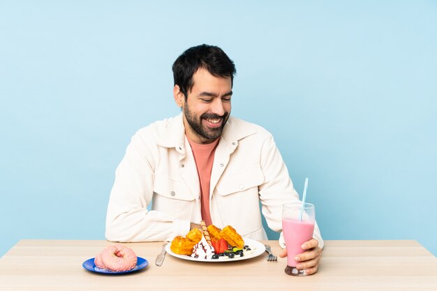 Homem em uma mesa tomando café da manhã waffles e um milk-shake