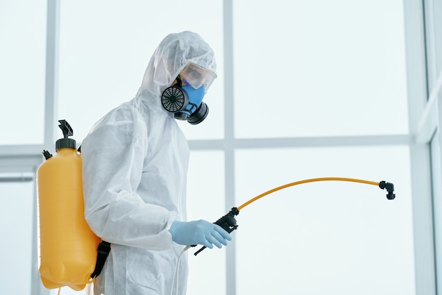 Homem em uma roupa de proteção bacteriológica em pé no escritório