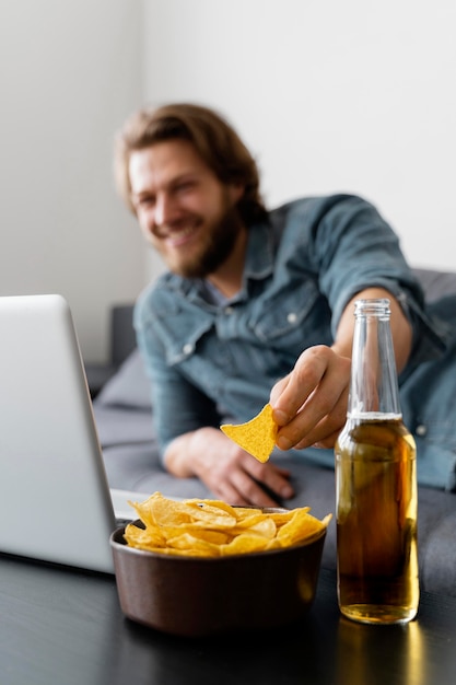 Homem embaçado no sofá com batatas fritas