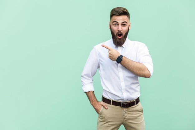 Foto homem emocional em camisa branca perto de fundo verde