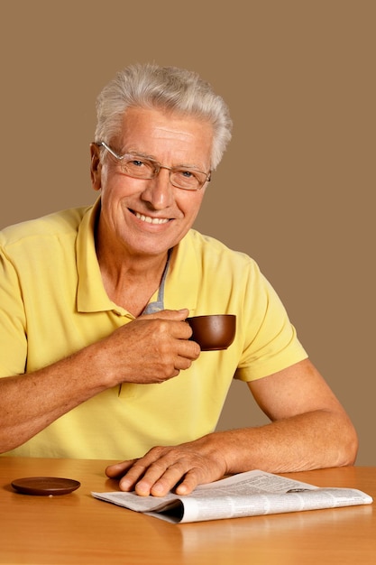 Homem emocional sênior lendo jornal e posando em segundo plano