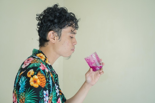 Homem encaracolado usa roupa de praia Segura um copo de suco de fruta do dragão com sorriso e pose de sede