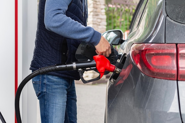 Homem enche seu carro preto com combustível no posto de gasolina bombeia injetor de gasolina para reabastecimento