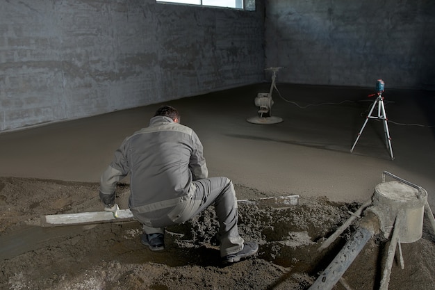 Homem enchendo o chão com concreto