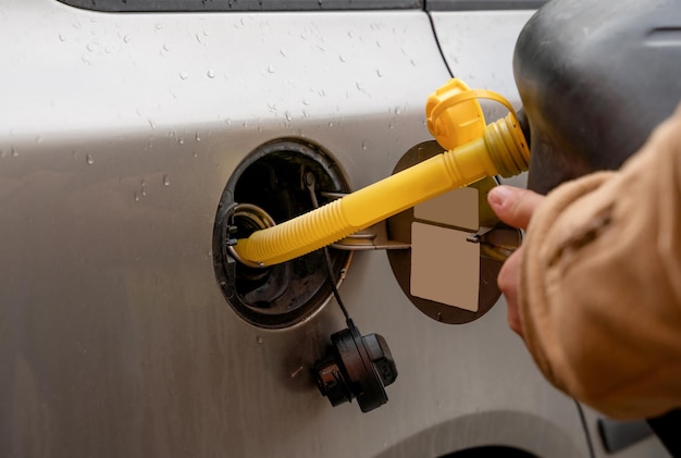 homem enchendo o tanque de combustível do carro com combustível diesel fora do jerry can, pois não há combustível no posto de gasolina