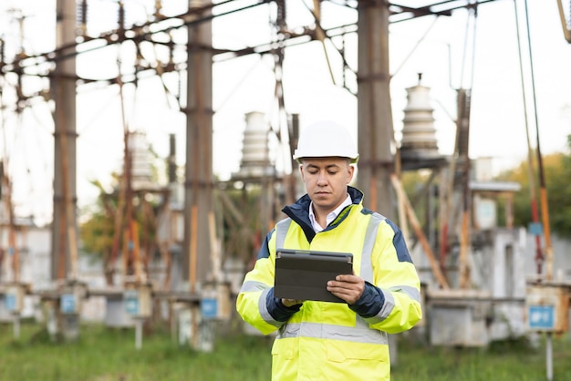 Homem engenheiro de energia com roupas especiais inspeciona uma linha de energia usando dados de sensores elétricos