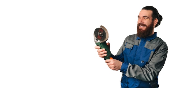 Homem engenheiro vestindo uniforme azul está segurando uma ferramenta elétrica de rebarbadora