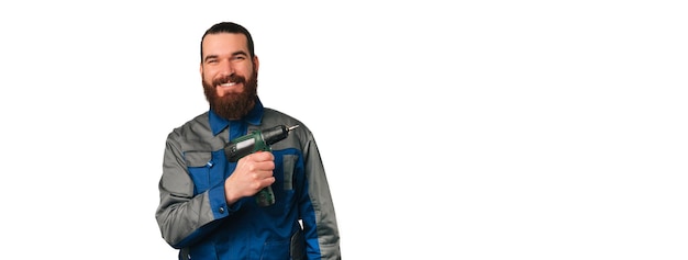 Homem engenheiro vestindo uniforme azul está segurando uma furadeira ou chave de fenda