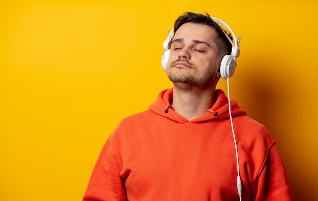 Homem engraçado com fones de ouvido na parede amarela