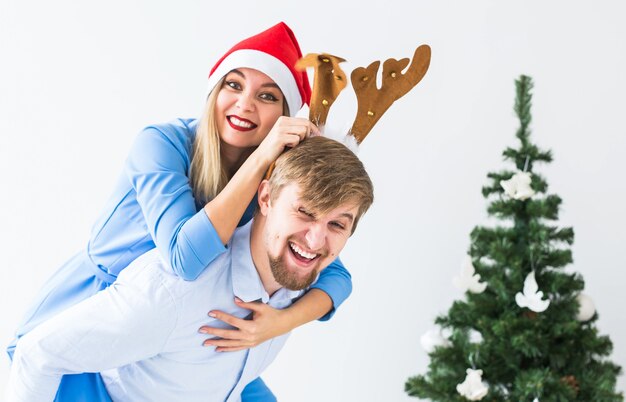 Homem engraçado dando carona para sua esposa enquanto eles usavam gorros de papai noel para as férias de natal em casa.