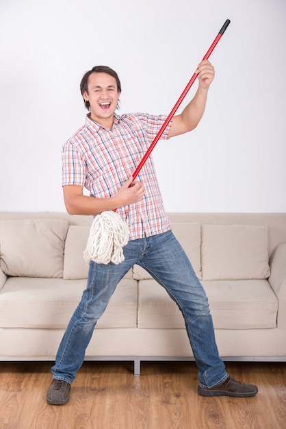 Homem engraçado é esfregar o chão e tocar música usando esfregão.