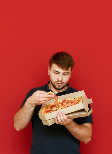 Foto homem engraçado faminto se levanta e tira uma fatia de pizza da caixa