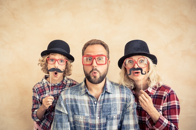 Foto homem engraçado, mulher e criança com bigode falso. família feliz brincando em casa