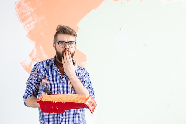 Homem engraçado pintando a parede em seu novo apartamento. Conceito de renovação, redecoração e reparação. cópia de