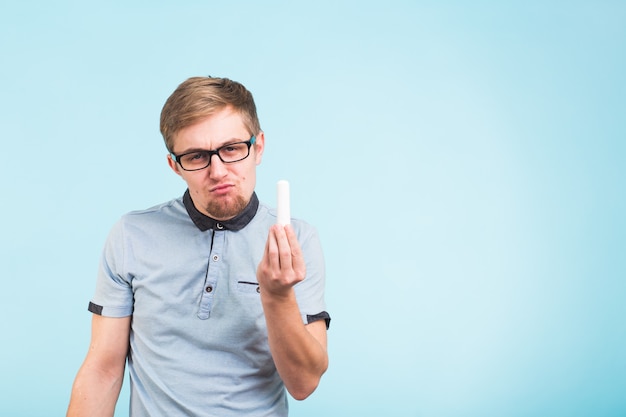 Homem engraçado sorridente usando óculos e roupas casuais segurando giz expressa emoções positivas