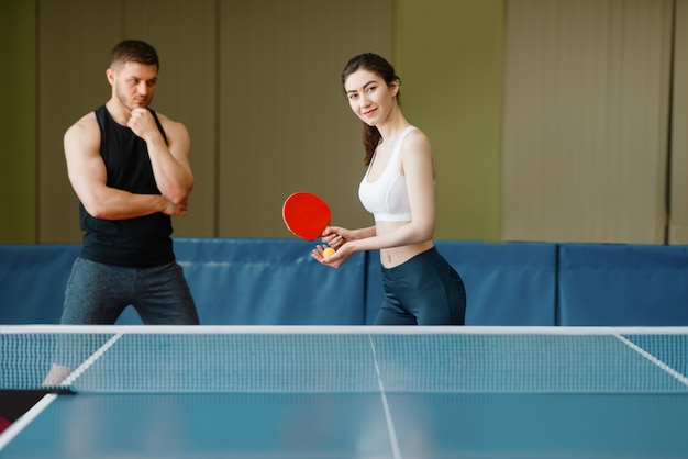 Homem ensina mulher a jogar pingue-pongue