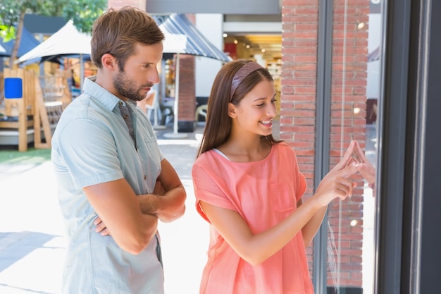 Homem entediado observando sua esposa feliz olhando uma janela