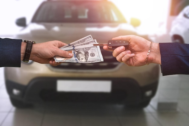 Homem entrega uma grande soma de dólares para outro que em troca passa as chaves de um carro comprado