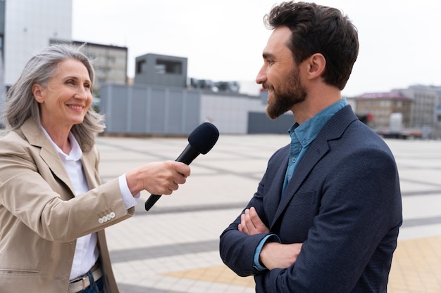 Homem entrevistado por jornalistas ao ar livre