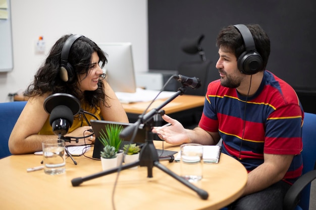 Homem entrevistando uma convidada durante a gravação ao vivo de um podcast ou programa de rádio