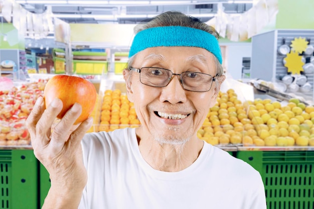 Homem envelhecido mostrando uma maçã saudável