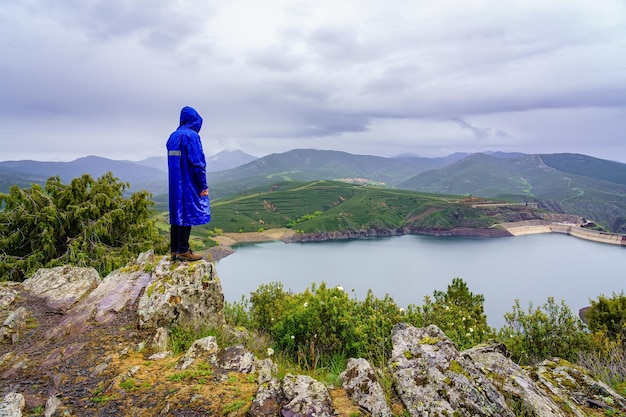 Homem escalou uma rocha no pico da montanha e contemplando o vale com o lago