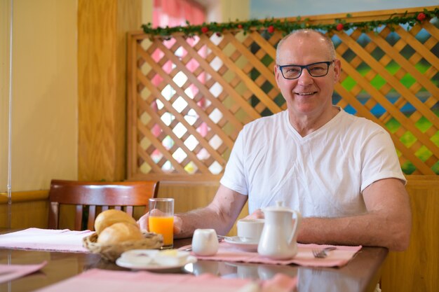 Homem escandinavo sênior sentado em um restaurante pronto para o café da manhã