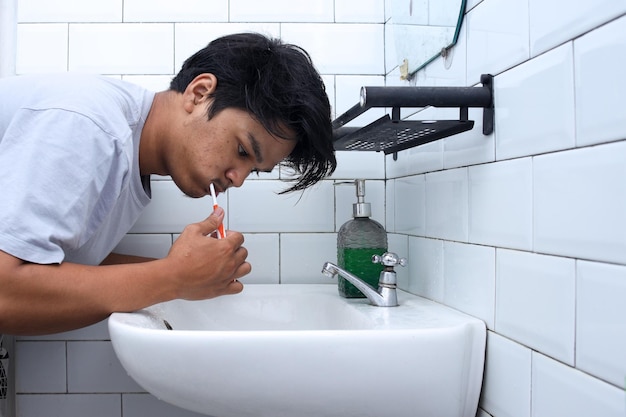 Homem escovando os dentes no banheiro Rotina de luto e conceito de higiene