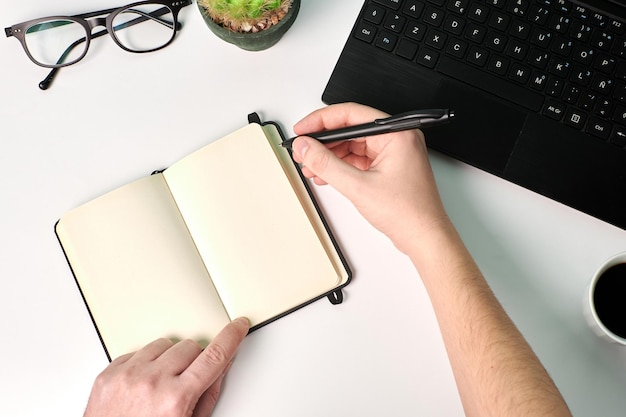 Homem escreve em um notebook em um fundo branco. Conceito de negócios