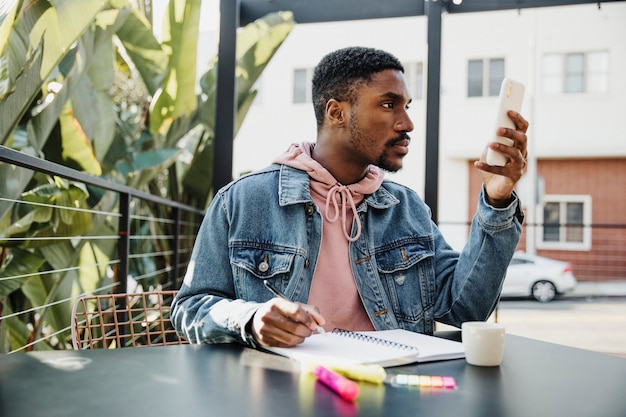 Homem escrevendo em seu caderno em um café