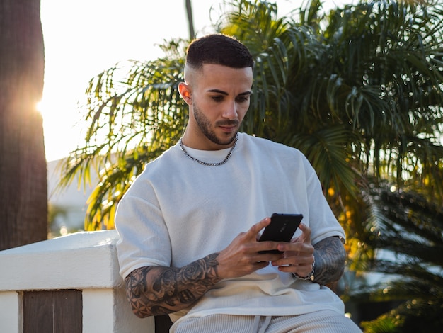 Homem espanhol bonito com tatuagens segurando um telefone