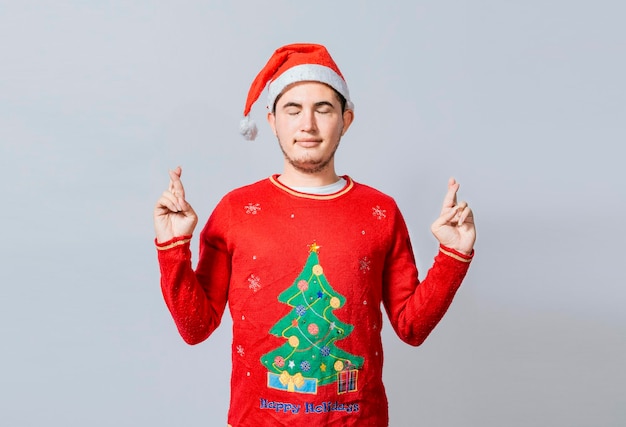 Homem esperançoso em roupas de natal, fazendo um desejo Homem bonito com chapéu de natal, fazendo um desejo no fundo branco Cara com chapéu de natal, fazendo um desejo no fundo isolado