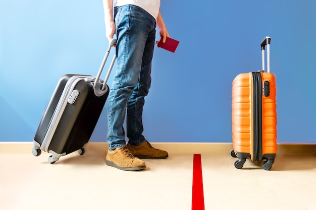 Homem esperando na marca de solo no aeroporto com uma mala preta