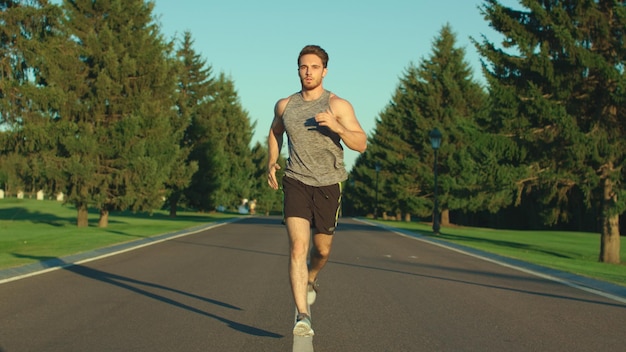 Homem esportivo correndo no parque de verão enquanto treina cardio ao ar livre Exercício de fitness