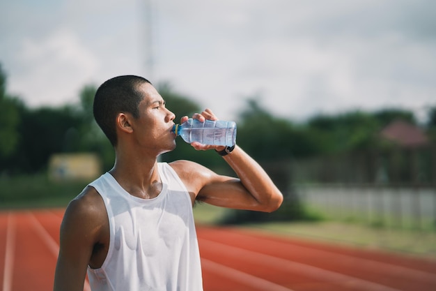 Homem esportivo segura o corredor de água de garrafa cansado e com sede depois de correr treino água potável Conceito de homem esportivo
