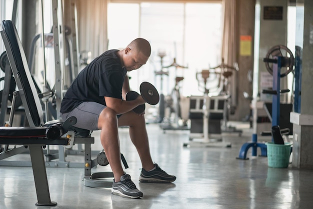 Homem esportivo usando exercícios com halteres no ginásio Musculação asiática para treinamento muscular Conceito de ginásio de saúde esportiva