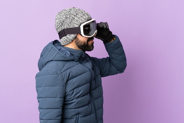 Homem esquiador com óculos de snowboard em roxo isolado