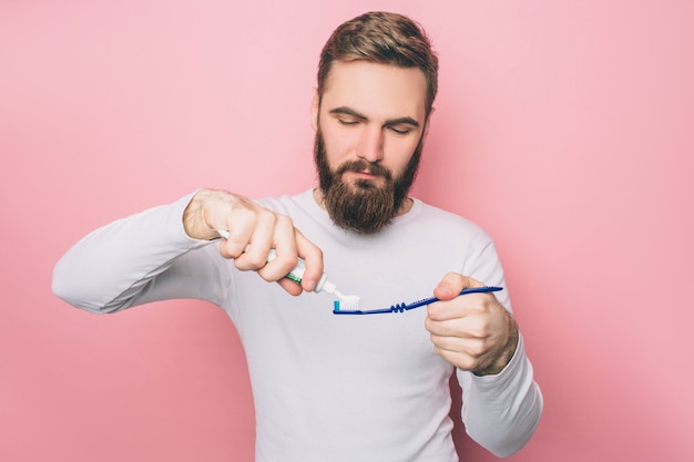 Homem está colocando um pouco de pasta de dente em uma escova de dente