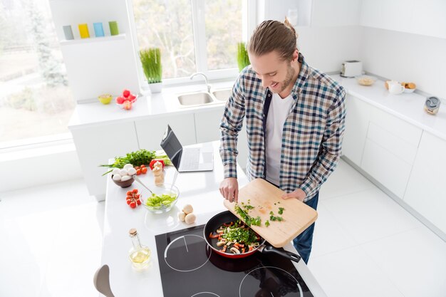 Homem está cozinhando em cozinha moderna