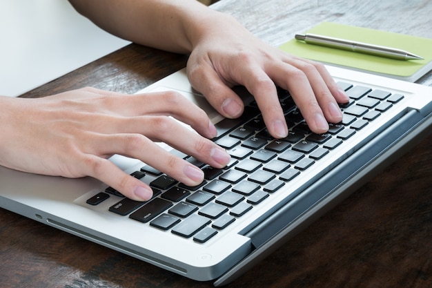 Homem está digitando no teclado do laptop.