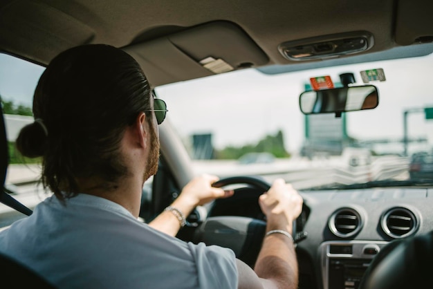 Homem está dirigindo um carro na rodovia durante uma viagem de estrada